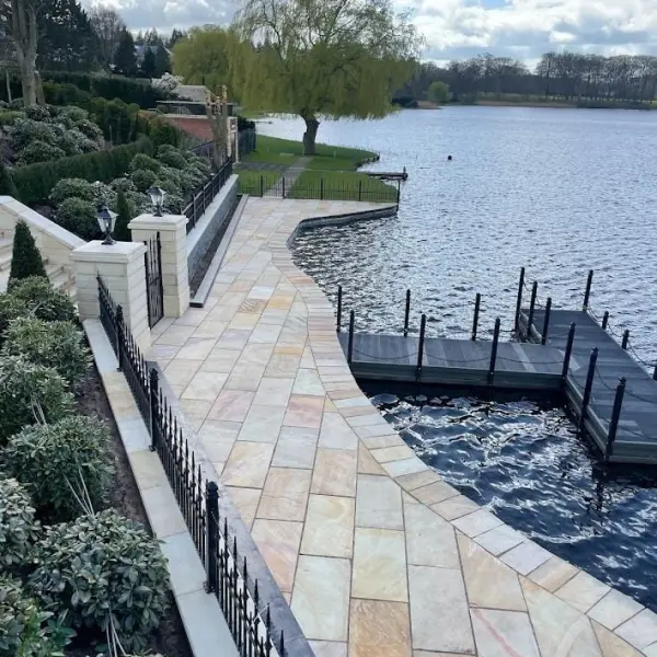 Freshly cleaned natural stone patio leading to a dock on a serene lakeside.