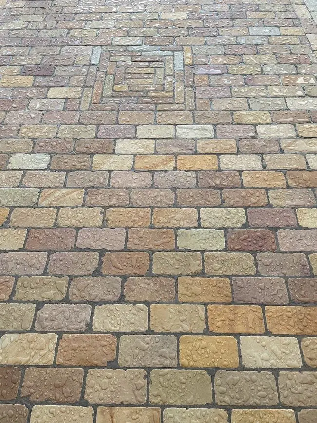 Wet colorful sandstone block driveway with water beading effect from HR Colour Enhancer impregnating sealer, enhancing the stone's natural colors.
