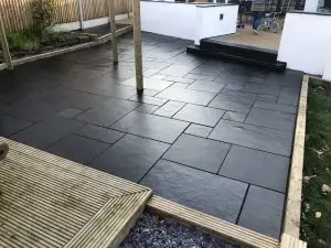 A black limestone patio mid-application of HR Colour Enhancer sealer.